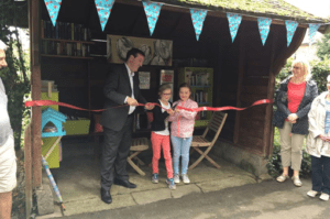 Mollington, Cheshire bus stop turned into a library, photograph of children cuttiing a ribbon at the opening